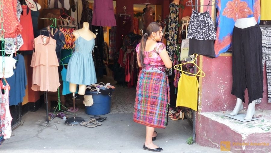 Domorodá obyvatelé San Pedra se oblékají do tradičních oděvů. Co si asi myslí mayská dívka před butikem?